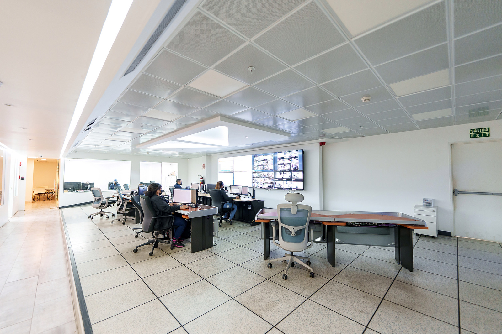 Operadores y consolas en una sala de monitoreo con videowall.