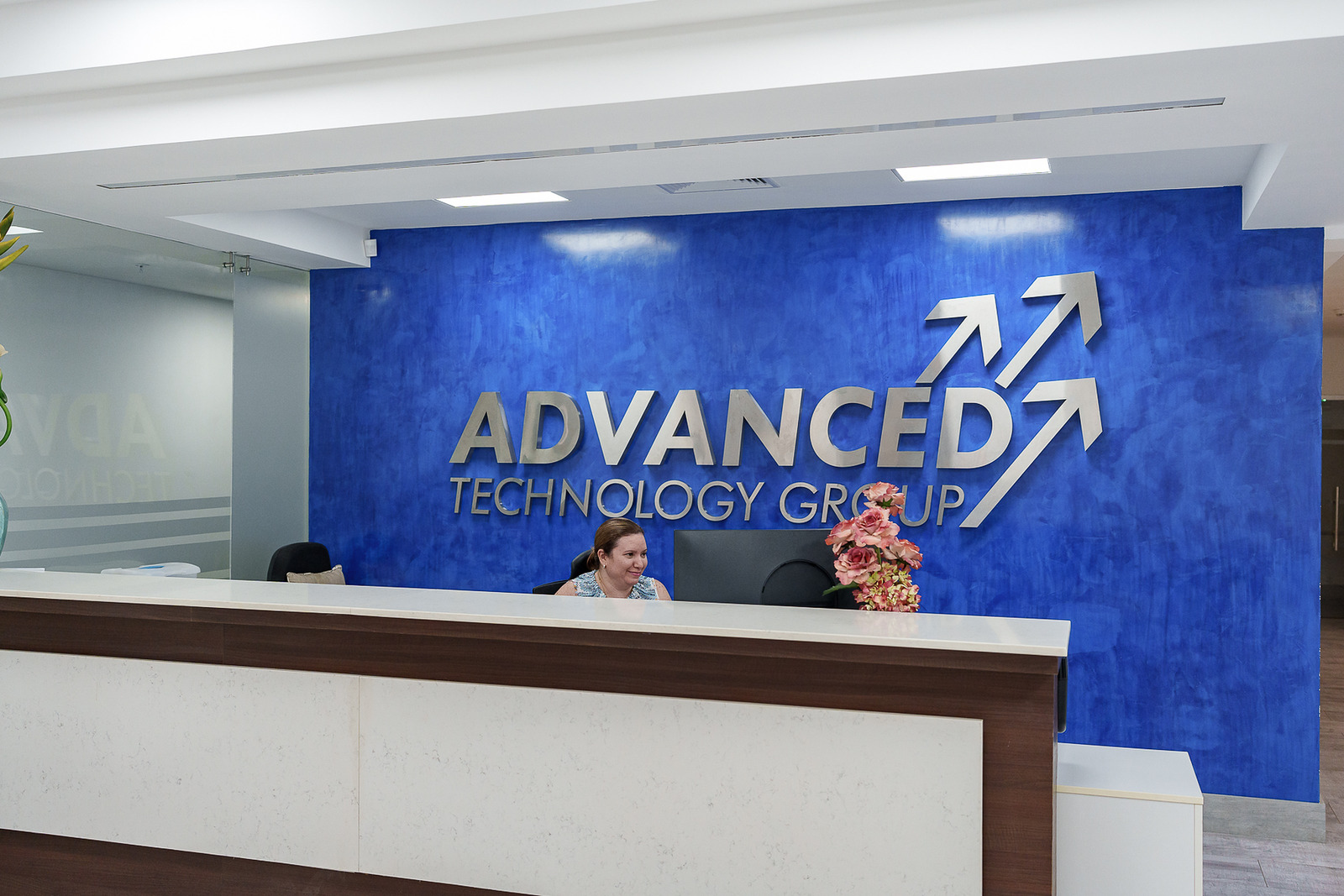Mostrador de recepción con el logo de Advanced Technology Group en una pared azul.